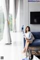 A woman sitting on a blue couch in a living room.