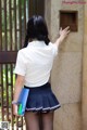 A woman in a school uniform is standing in front of a door.