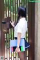 A woman in a school uniform holding a cell phone and a folder.