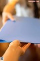 A person holding a piece of blue paper in their hands.