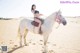 A woman riding on the back of a white horse.