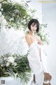 A woman in a white dress standing next to a bunch of flowers.