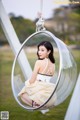 A woman sitting in a hanging chair in a park.