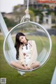 A woman sitting in a hanging chair in a park.