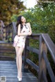 A woman in a white dress standing on a wooden bridge.