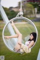 A woman laying in a hanging chair in a park.