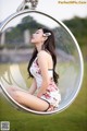 A woman sitting in a bubble chair in a park.