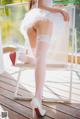 A woman in a white dress and high heels sitting on a chair.