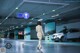 A woman walking in a parking garage next to a car.