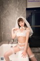 A woman in a white lingerie sitting in a bathtub.