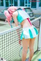 A woman with pink hair standing on a tennis court.