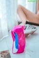 A woman sitting on the floor next to a pink bag.