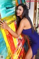 A woman in a blue dress leaning against a colorful painting.