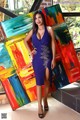 A woman in a blue dress standing in front of a colorful painting.