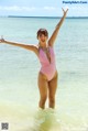 A woman in a pink bathing suit standing in the ocean.