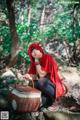 A woman in a red hoodie sitting on a rock with a basket.