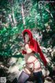 A woman dressed as a red riding hood in the woods.