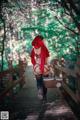 A woman in a red riding hoodie is walking across a bridge.