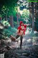 A woman dressed as a red riding hood in the woods.