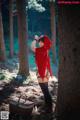 A woman dressed as a little red riding hood in the woods.