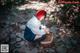 A woman sitting on a rock with a picnic basket.