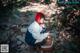 A woman sitting on a rock with a picnic basket.