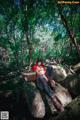 A woman sitting on a rock in the woods.