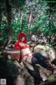 A woman in a red riding hoodie sitting on a rock.