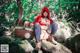 A woman dressed as a red riding hood sitting on a rock.