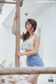 A woman leaning against a wooden pole on a balcony.