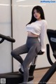 A woman in a white shirt and gray leggings on a stationary bike.