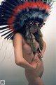 A naked woman wearing an indian headdress poses for a picture.