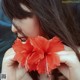 A woman holding a red flower in front of her face.