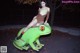 A woman sitting on top of a green frog statue.