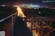 A naked woman standing on a bridge at night.