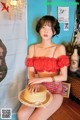 A woman sitting on a wooden floor wearing a straw hat.