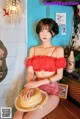 A woman sitting on a wooden floor wearing a straw hat.