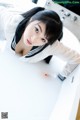 A woman in a white shirt is taking a bath in a bathtub.