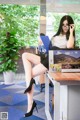 A woman sitting at a desk with a laptop and a book.