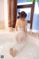 A woman in a white dress sitting in a bathtub.