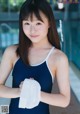 A woman in a blue bathing suit holding a white towel.