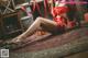 A woman in a red lingerie sitting on the floor.