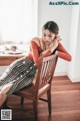 A woman sitting on a wooden chair in a room.