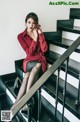 A woman in a red shirt and black skirt sitting on a set of stairs.