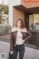 A woman wearing a brown leather jacket with a fur collar.