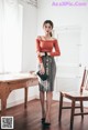 A woman standing in front of a wooden table.