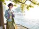 A woman in a blue and green hanbok standing on a dock.