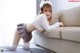 A woman in a school uniform is posing on a couch.