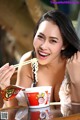 A woman sitting at a table eating noodles with chopsticks.