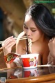 A woman eating a bowl of noodles with chopsticks.